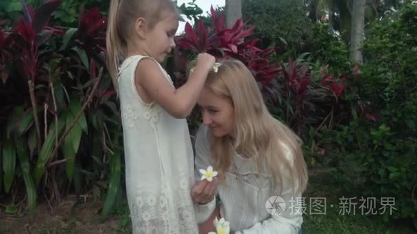 小女孩装饰母亲头插鲜花的鸡蛋花素材视频