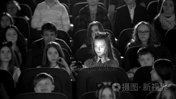 黑白图片。美丽的小女孩厅影院里看着自己。多的孩子坐
