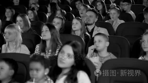 黑色和白色开枪。儿童在电影院大厅里热情地寻找开朗卡通