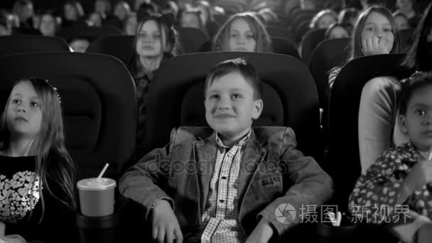 漂亮的男孩，很多的小女孩，在电影院看电影。关闭了画像。开枪的黑色和白色