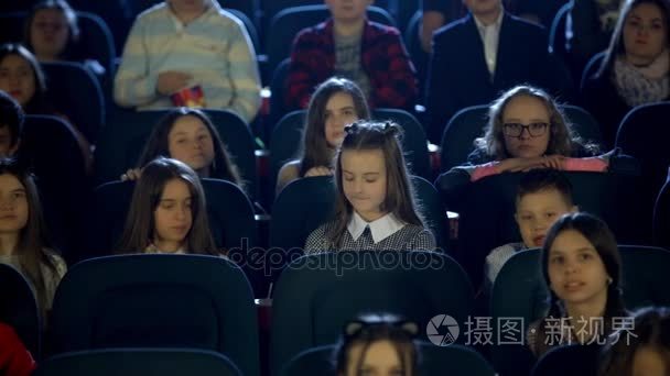 美丽的小女孩厅影院里看着自己。多的孩子坐