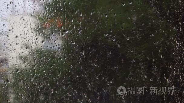 雨点落在玻璃窗口与模糊的绿色自然背景上