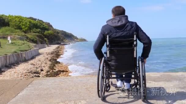 残疾男子坐轮椅在海滩后面