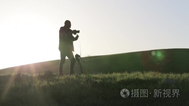 摄影师拍摄相机和三脚架山顶视频