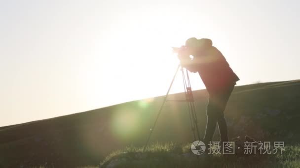 摄影师拍摄相机和三脚架山顶视频