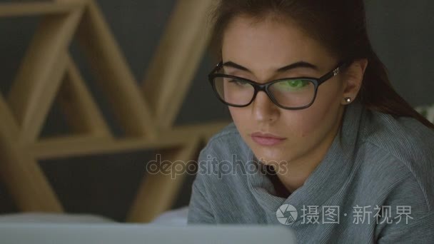 年轻女子戴着眼镜看着监视器，上网冲浪