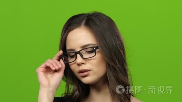 戴眼镜的女孩开始调情和性摘掉眼镜。绿屏。关闭