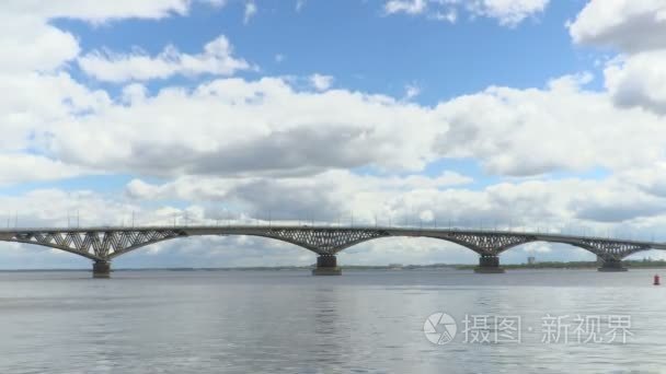 伏尔加河畔的萨拉托夫城市和恩格斯之间跨海公路大桥。时间流逝的河风光。漂浮在天空。桥上的车辆的运动。夏季的一天。俄罗斯