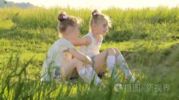 两个小女孩坐在草地谈上有乐趣视频