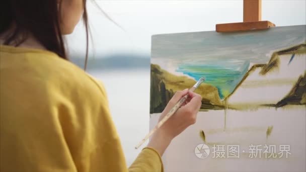 女画家在画布上，站在画架一幅油画