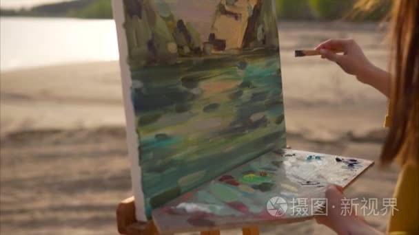 女艺术家混合在调色板上她是在露天的画架油画颜料