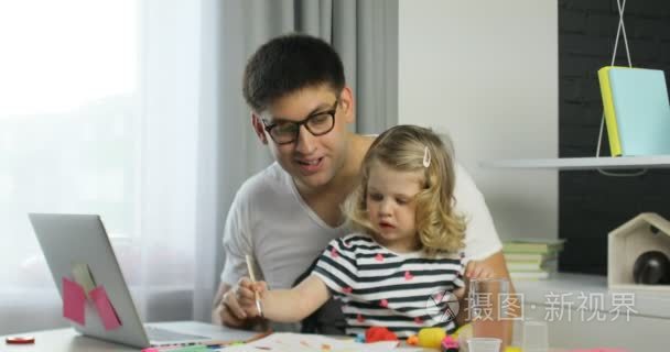 年轻英俊的男子，戴着眼镜，她女儿与卷曲金发绘图使用家庭背景上的油漆。室内