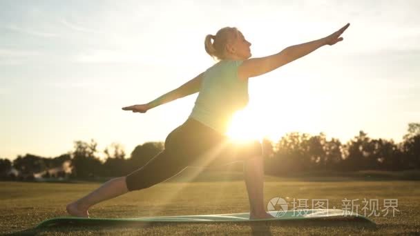 成人健康的女人，在日落时练瑜伽