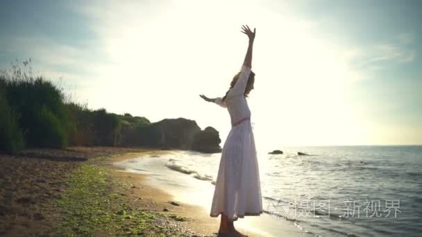 女性美健康浪漫的自由女人练习瑜伽砂海洋黎明慢动作