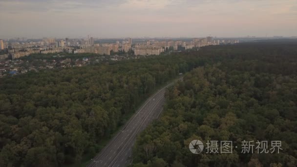 汽车行驶道路位于市线附近的绿树丛中。鸟瞰图