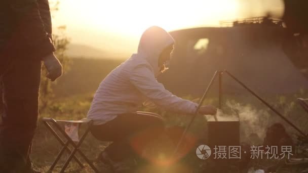 家庭烹饪晚餐在营火在日落时视频