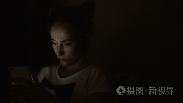 累了伤感的女子在夜间使用手机视频