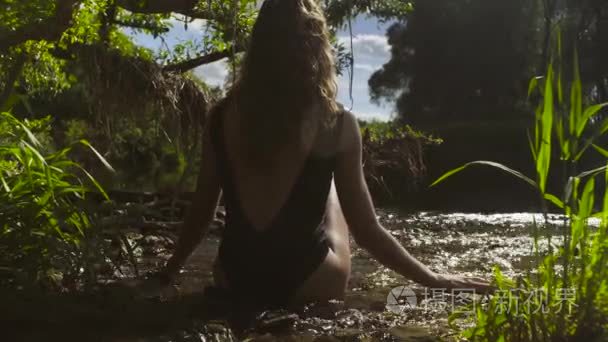 坐在河边浅水的年轻女人视频
