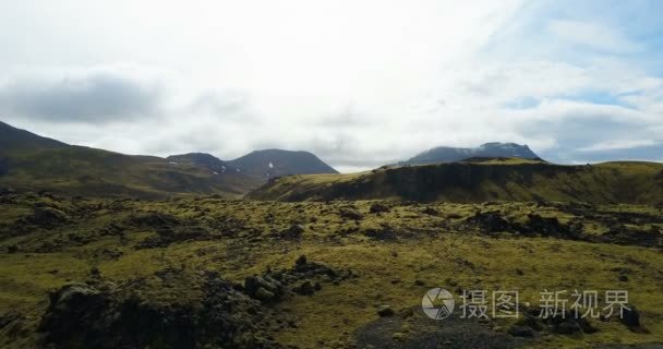 在冰岛的熔岩字段的鸟瞰图。直升机飞越长满了苔藓绿山在阴天