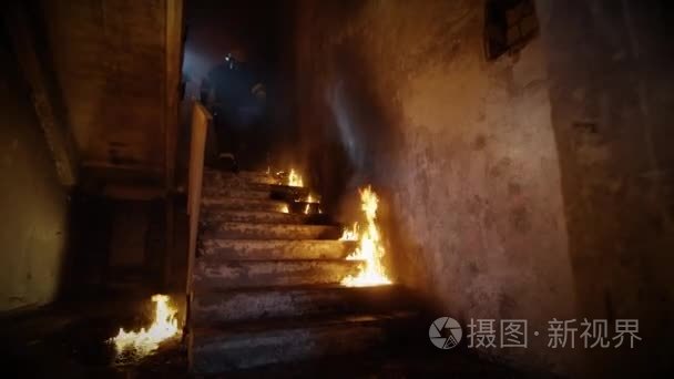 两名消防员血统上燃烧的楼梯，走进敞开大门。建筑是在火上。火是看到无处不在视频