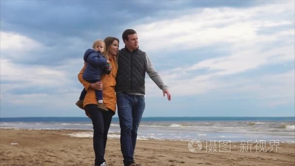 父母带着小女儿在海边散步，在寒冷的冬日