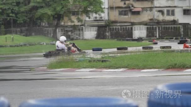 卡丁车-在头盔上卡丁车电路的驱动程序。成人卡丁车赛车在赛道上。在赛道的阴雨天气。慢动作