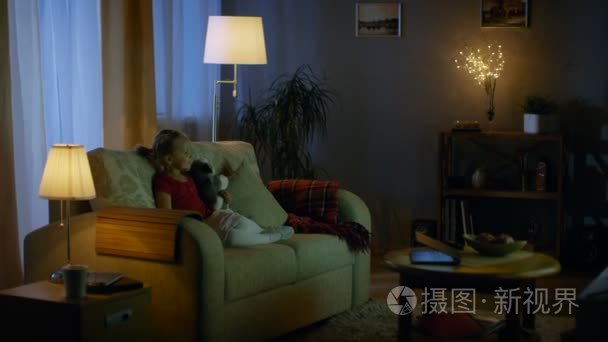 在晚上可爱的小女孩正坐在客厅沙发上,她看电视.