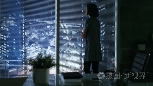 女商人入她私人办公室窗外的大城市看起来华丽然后坐在她办公桌。她的工作区看起来现代与暗色调