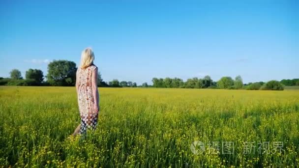 替身拍摄： 年轻女人走在一个开花的草甸，后视