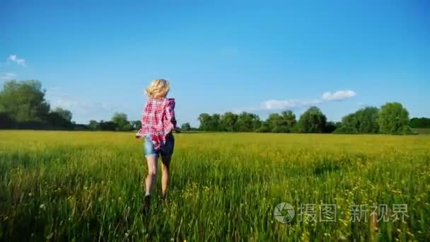 无忧无虑的女人贯穿开花草甸。斯坦尼康来拍摄镜头