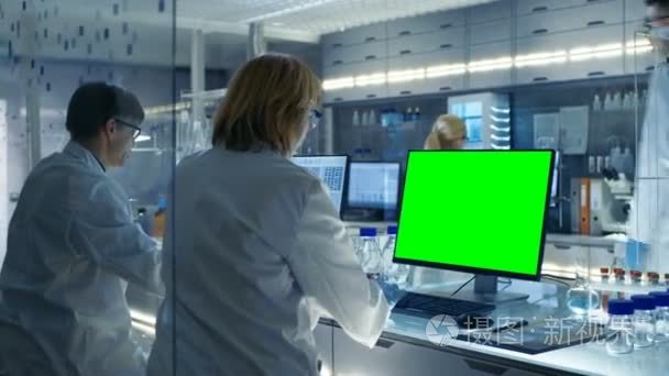 女性和男性科学家们致力于他们的现代实验室计算机 （模拟绿色屏幕） 中。各种货架与烧杯、 化学品和不同的技术设备是可见