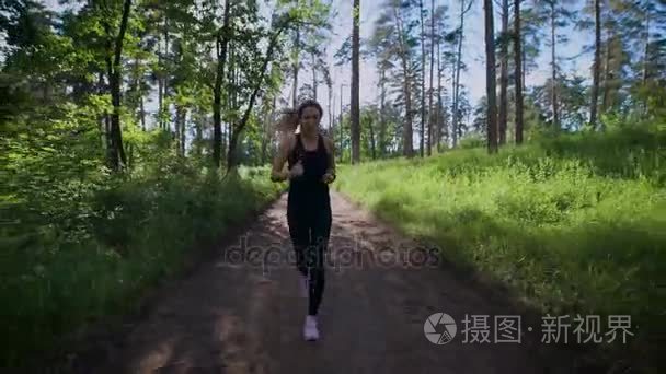 合适的嬉戏女人在绿色森林路上独自慢跑