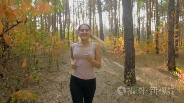 慢动作拍摄的美丽的年轻女子，慢跑在秋天的树林