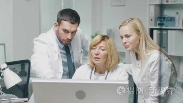 医疗人员讨论工作相关问题同时使用个人电脑。他们指着屏幕和谈话