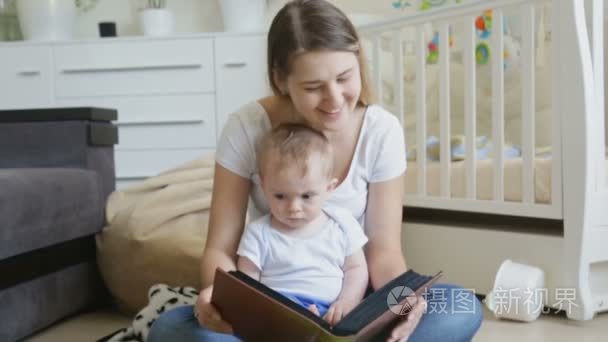 快乐的年轻母亲与她的宝贝儿子在客厅的地板上，看家庭相册