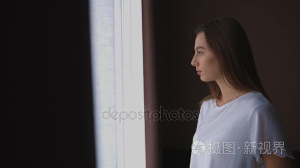 肖像的年轻女子 stending 在客厅窗户边上，对着镜头转身微笑