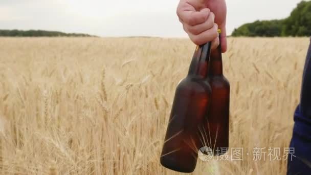 一名男子携带两瓶冰镇啤酒大麦的域上。这一概念是解渴。慢动作视频