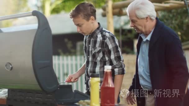 祖父和 Grandon 烹饪烤架上的汉堡在明亮夏季的一天视频