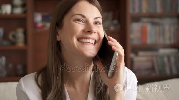 慢动作女人在家里谈移动电话。在智能手机上的随意交谈的美丽年轻女性专业