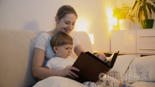 母亲阅读本书给她的宝贝儿子在床上的 4 k 镜头。