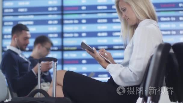 成人商务美女使用机场在候机室的平板电脑同时等待登机