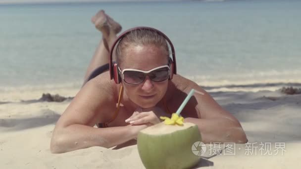 耳机在沙滩上躺着看椰子的女孩视频