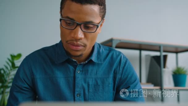 集中在办公室使用便携式计算机的非洲裔美国商人。男人在笔记本电脑键盘上打字。关闭
