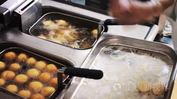 在热沸油中油炸锅做饭。厨师正在准备食物。美味的高脂肪食物。快餐食品