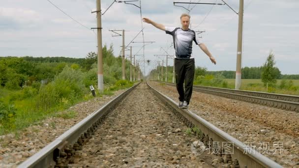 一名男子在运动服走在铁轨上视频