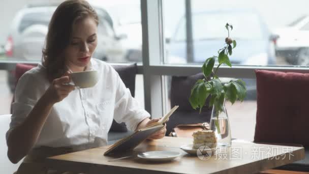 阅读本书和放松在咖啡馆里的女孩。在午休时休息的业务衣服的女孩