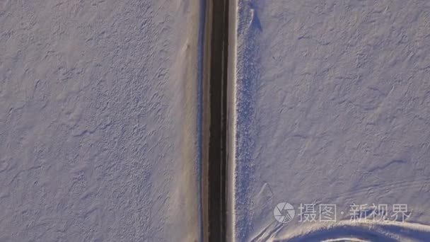 白雪覆盖的田地和道路的鸟瞰图。Suv 在冬季道路穿过雪地上开车。鸟瞰图的路和的字段在冬天驾驶的汽车