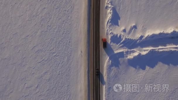 白雪覆盖的田地和道路的鸟瞰图。Suv 在冬季道路穿过雪地上开车。鸟瞰图的路和的字段在冬天驾驶的汽车