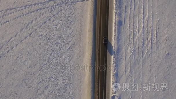 白雪覆盖的田地和道路的鸟瞰图。Suv 在冬季道路穿过雪地上开车。鸟瞰图的路和的字段在冬天驾驶的汽车