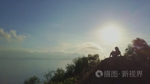 女孩坐在陡峭的悬崖上放松视频